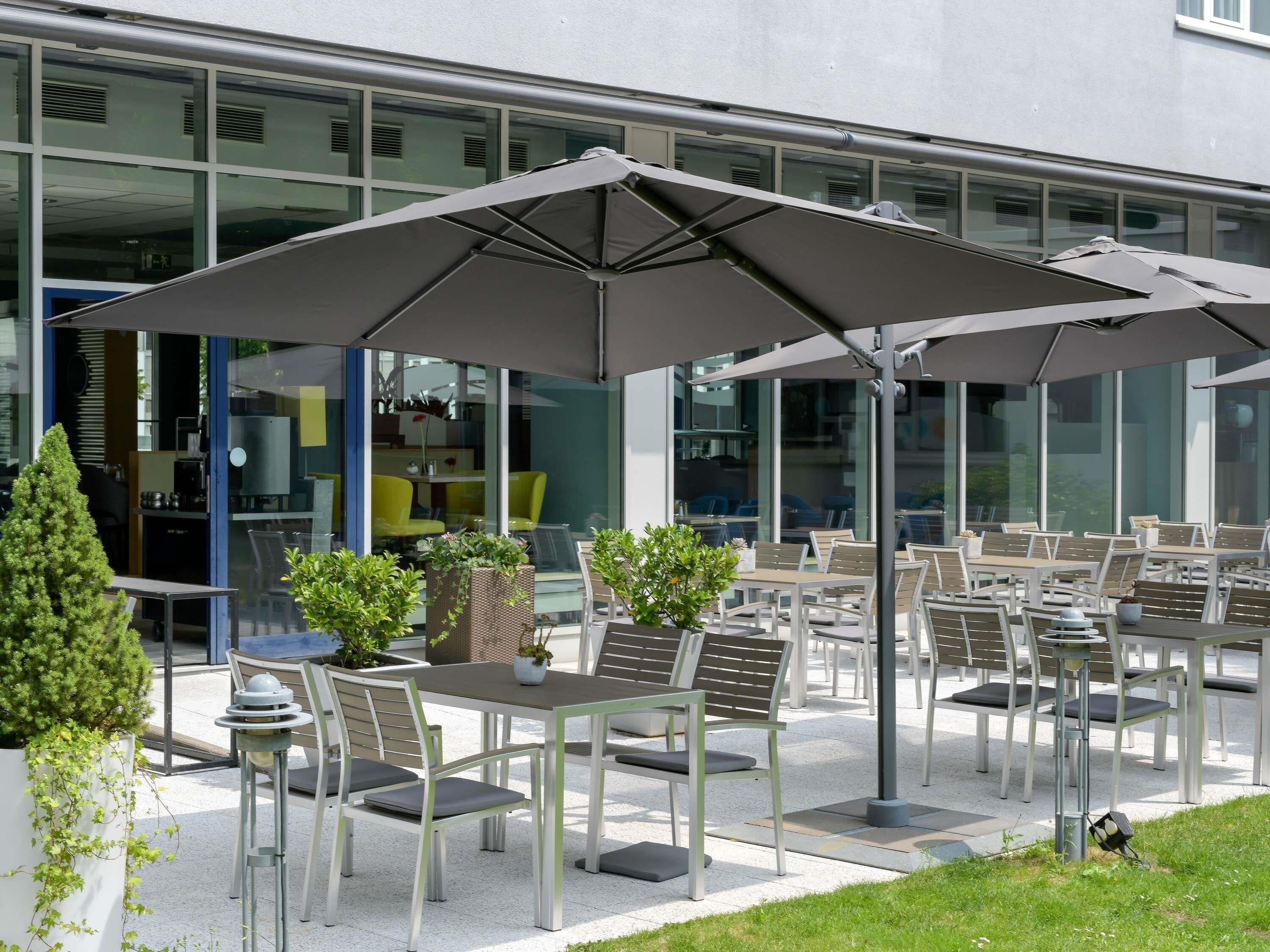 Un espace extérieur aménagé avec des tables, des chaises, des parasols et des plantes en pot.