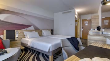 A modern hotel room with a bed, a desk, a chair, and a small table.