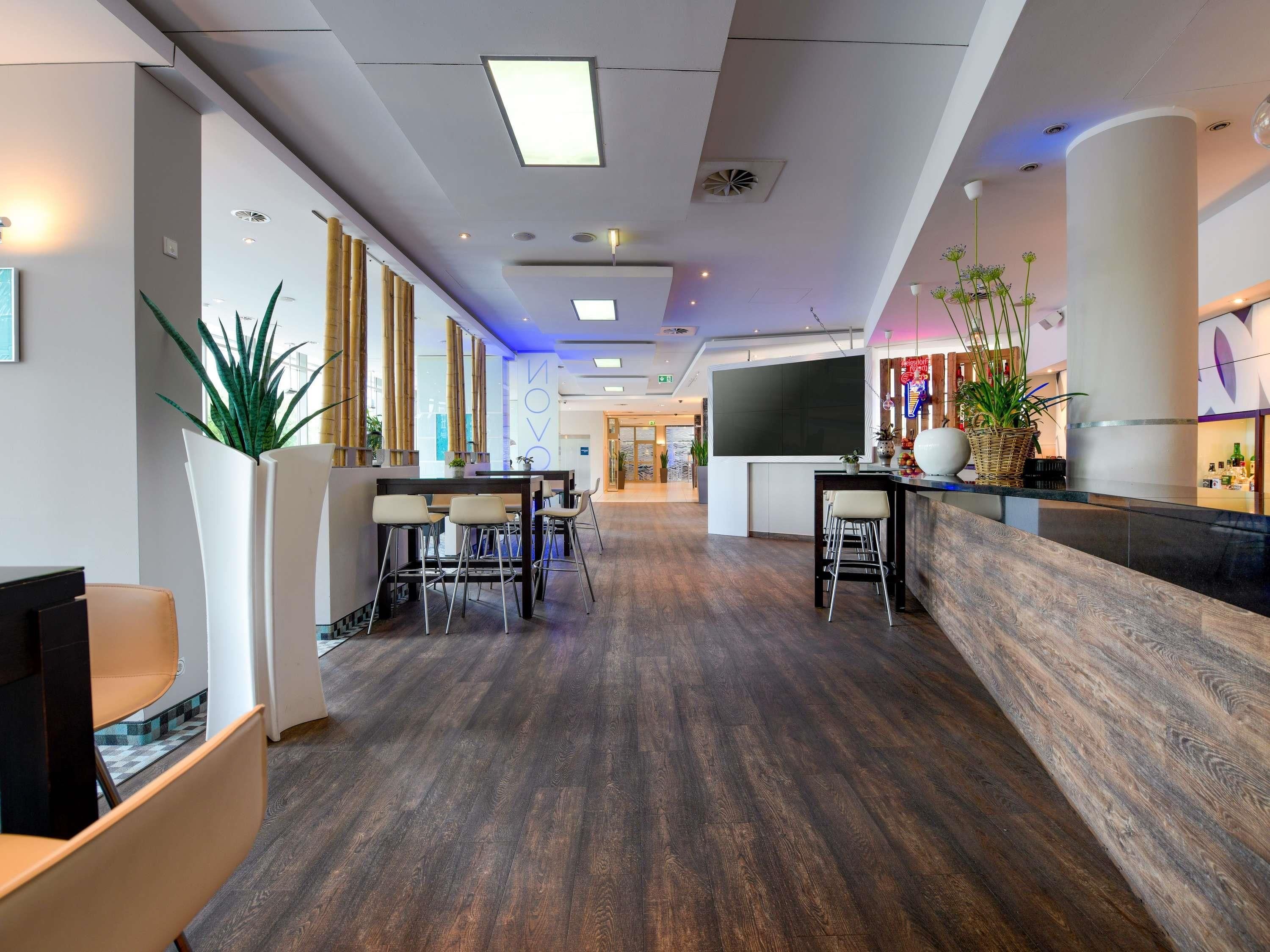 En moderne hotellobby med receptionsdisk, siddeområde og et stort vindue.
