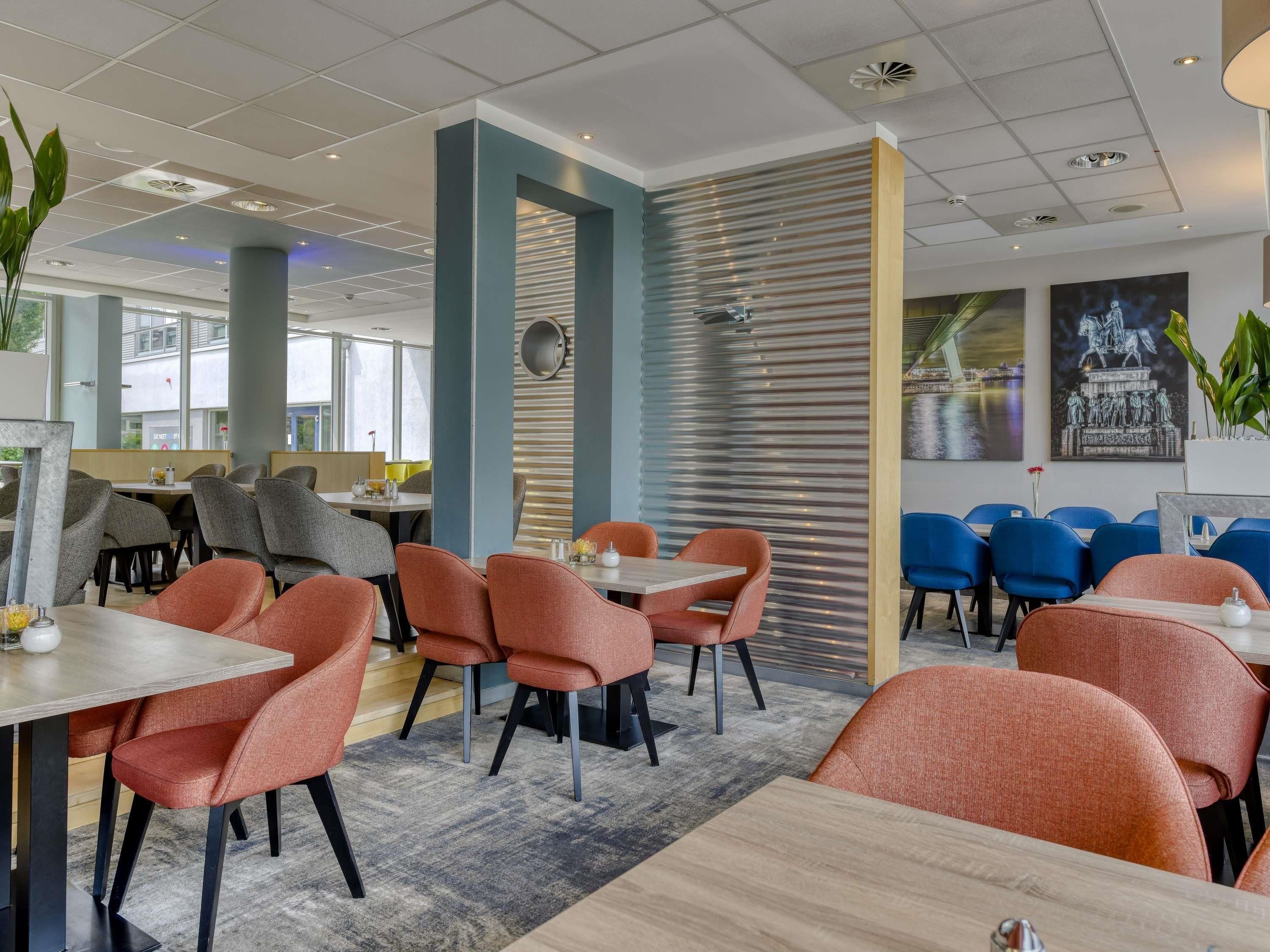 A modern dining area with tables and chairs, a patterned wall, and a large window.