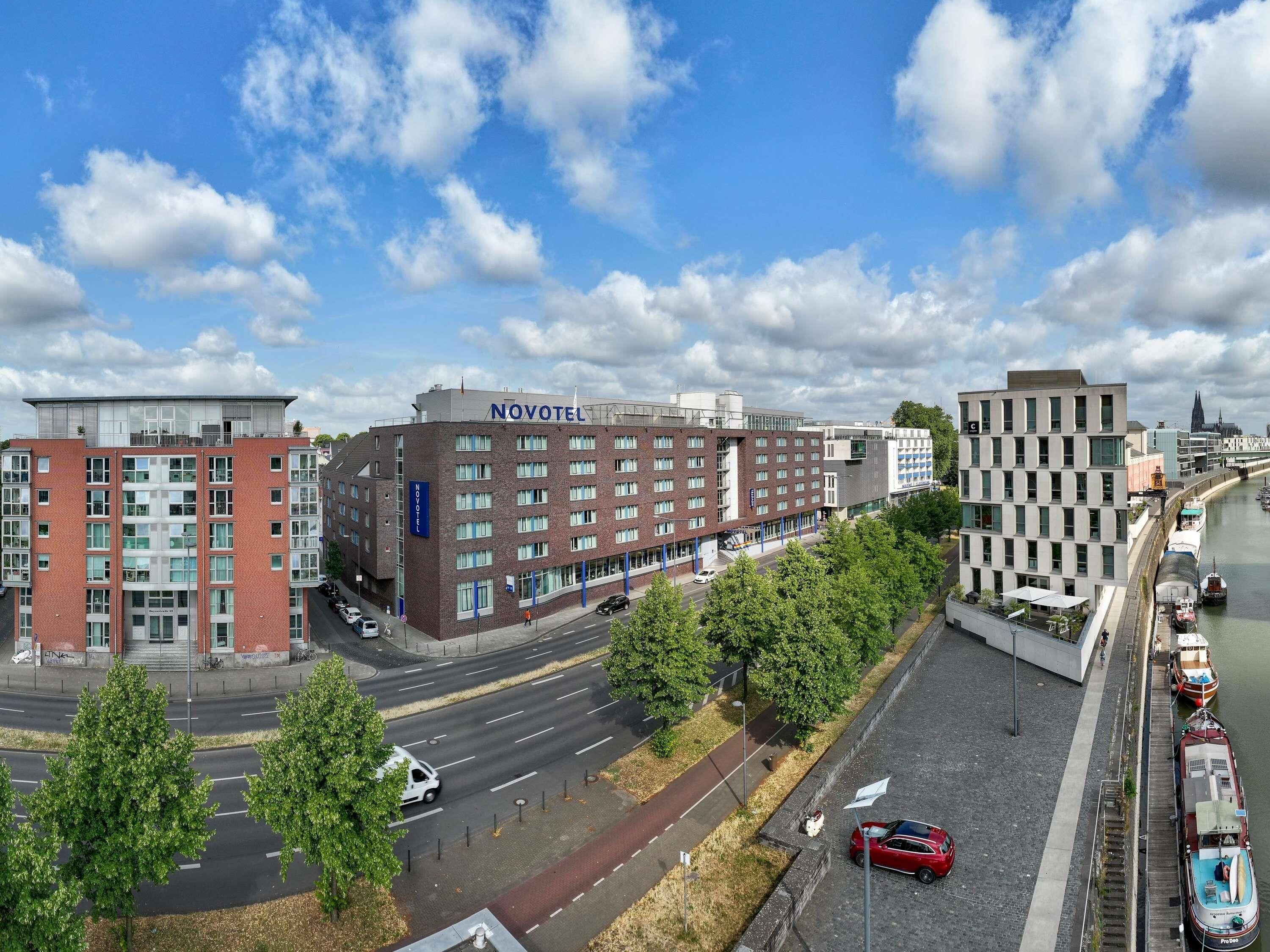 Ein Novotel Hotel mit moderner Ziegel Fassade, in der Nähe eines Flusses mit dort angestuften Booten.