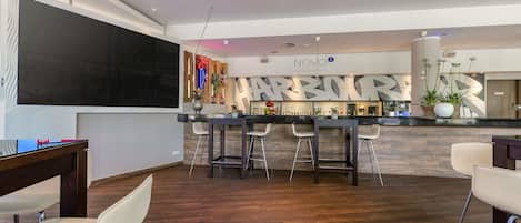 A modern bar area with a counter, bar stools, and a neon sign.