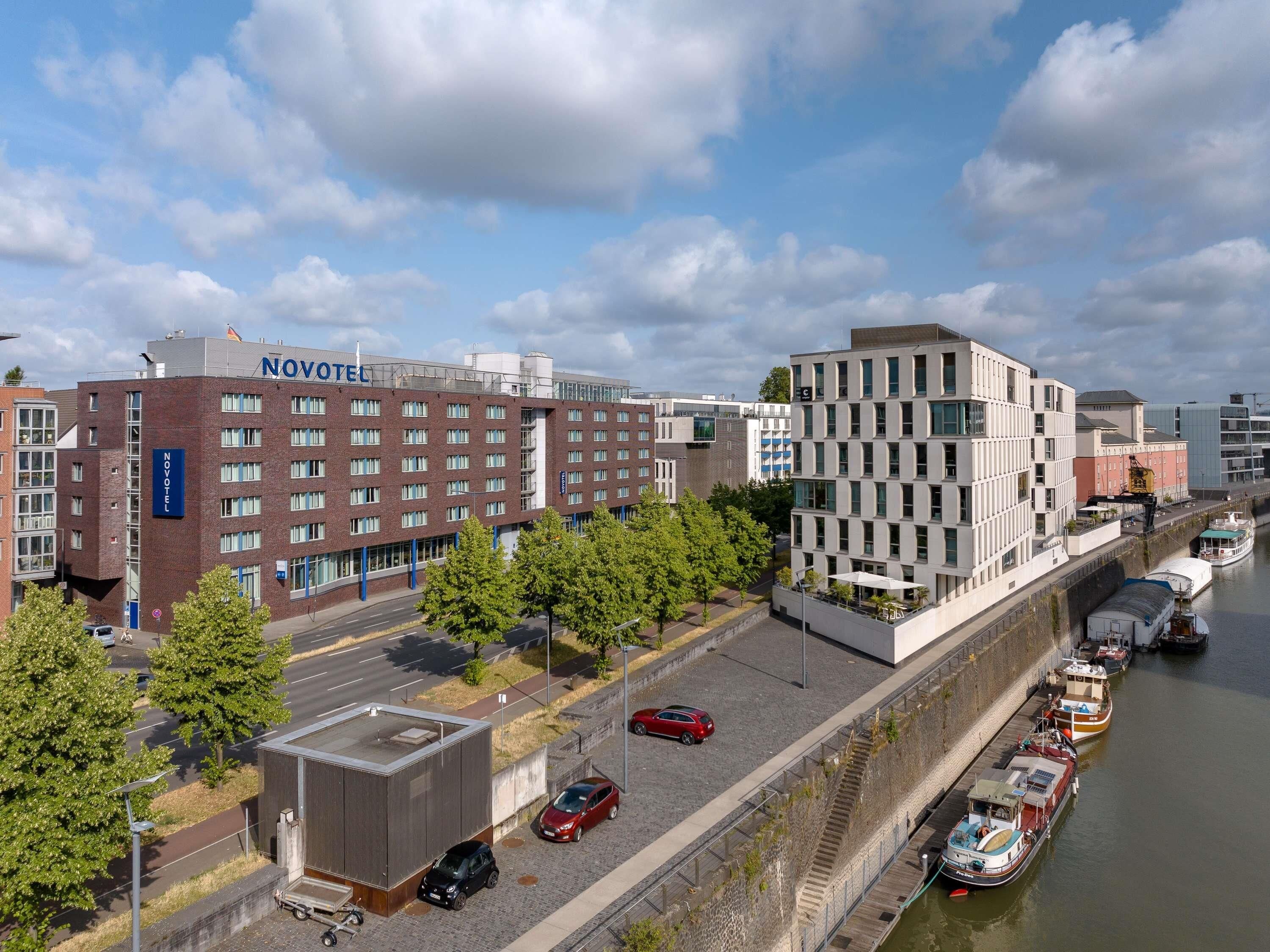 A Novotel hotel with a modern design, a riverside location, and a dock with boats.