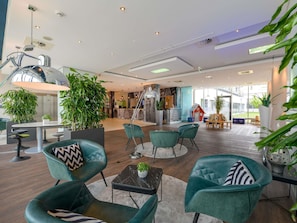 A modern interior with teal chairs, a reception desk, and a staircase.