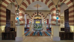 Eine Lobby mit gestreiften Bögen, einer Kristallleuchtre und einem zentralen Tisch mit Blumen.