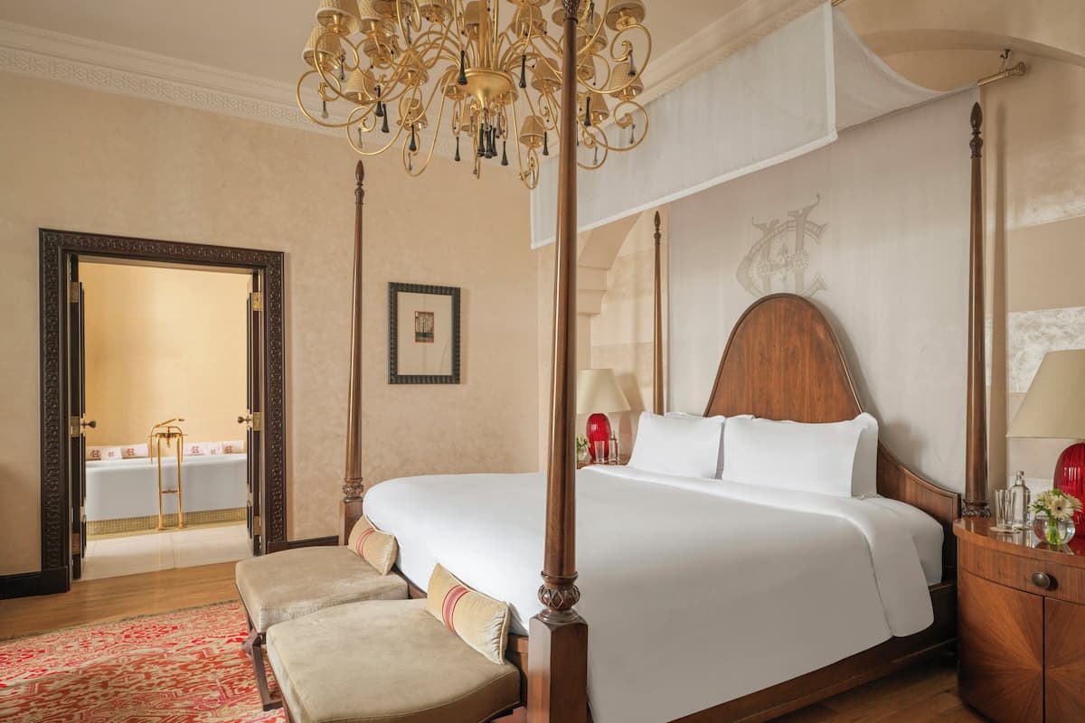 A four-poster bed with a canopy, a wooden nightstand, a bedside table, and a red patterned rug.