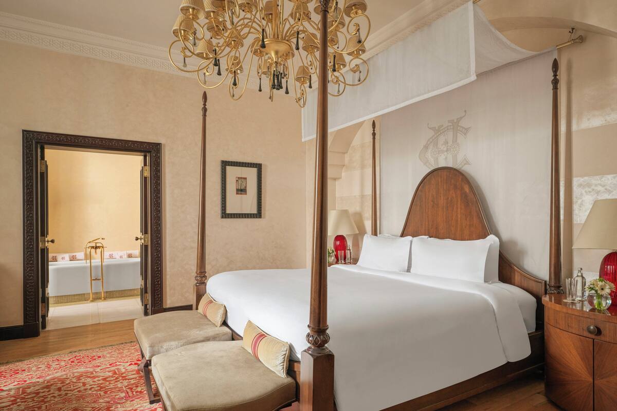 A four-poster bed with a canopy, a wooden nightstand, a bedside table, and a red patterned rug.