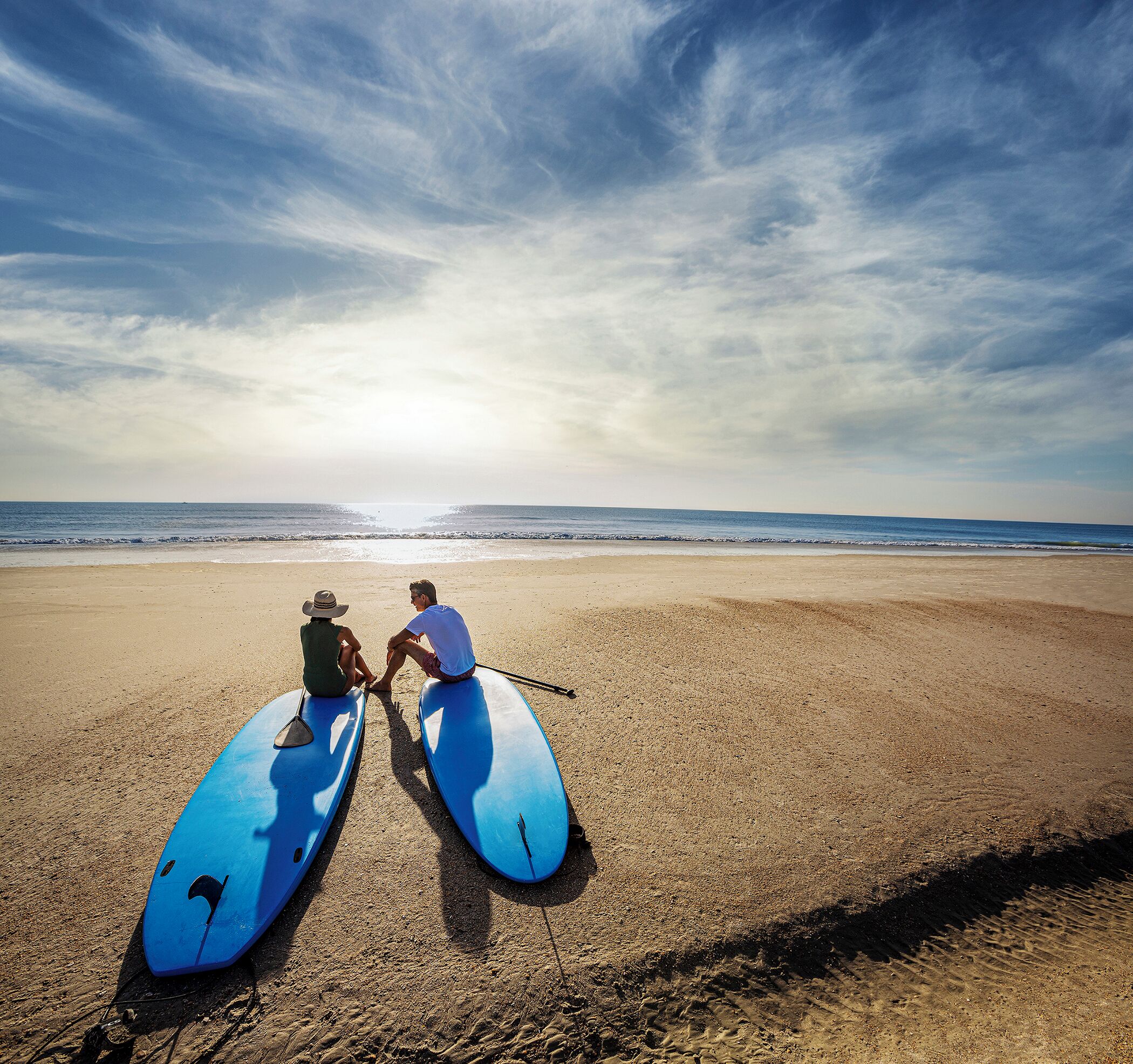 Two kayaks on a sandy beach with a clear sky.