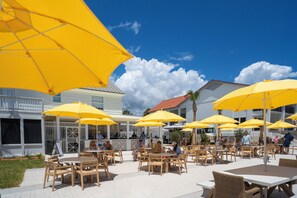 An outdoor patio area with yellow umbrellas, wooden tables, and chairs.