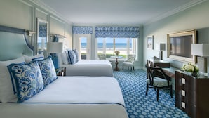 A hotel room with two beds, a desk, a chair, a TV, and a view of the ocean. - Ponte Vedra Inn & Club (Ponte Vedra Beach)