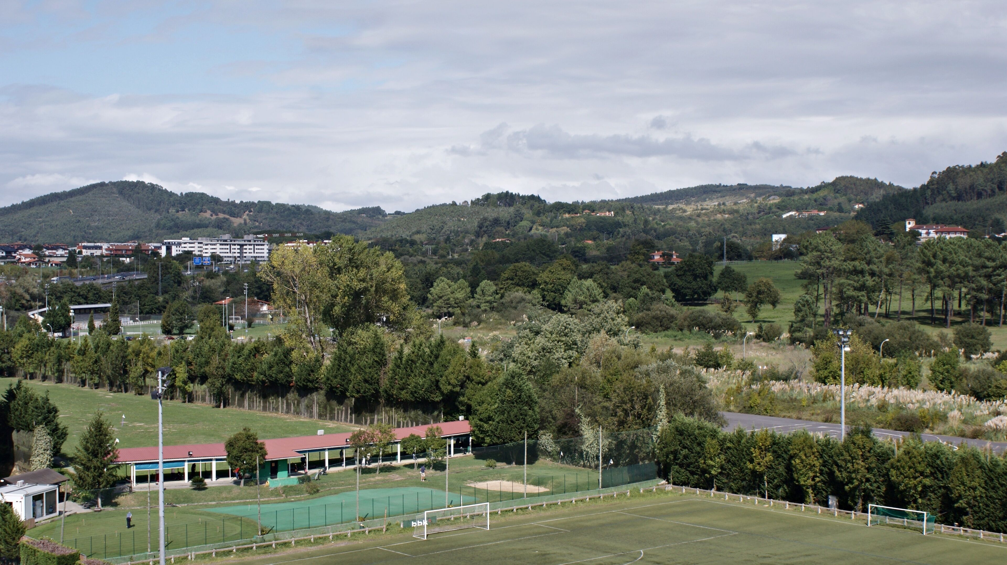 A sports field with a green pitch, goalpost, and surrounding fencing.