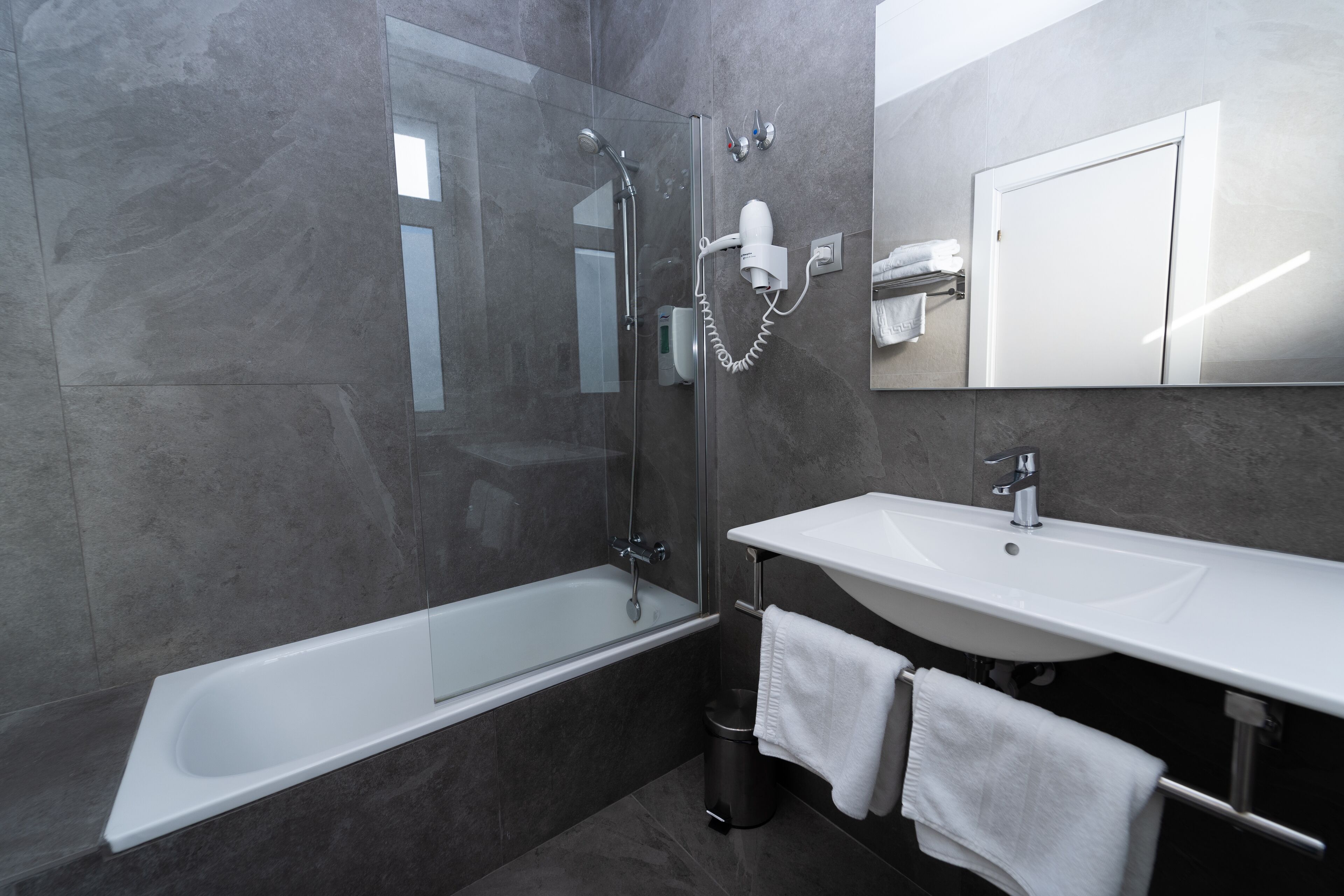 Une salle de bain moderne avec une douche à parois de verre, un lavabo blanc et un grand miroir.