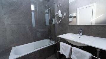 Une salle de bain moderne avec une douche à parois de verre, un lavabo blanc et un grand miroir.