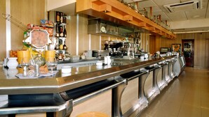 Uma área de bar com um balcão extenso, banquetas e uma variedade de garrafas e copos.