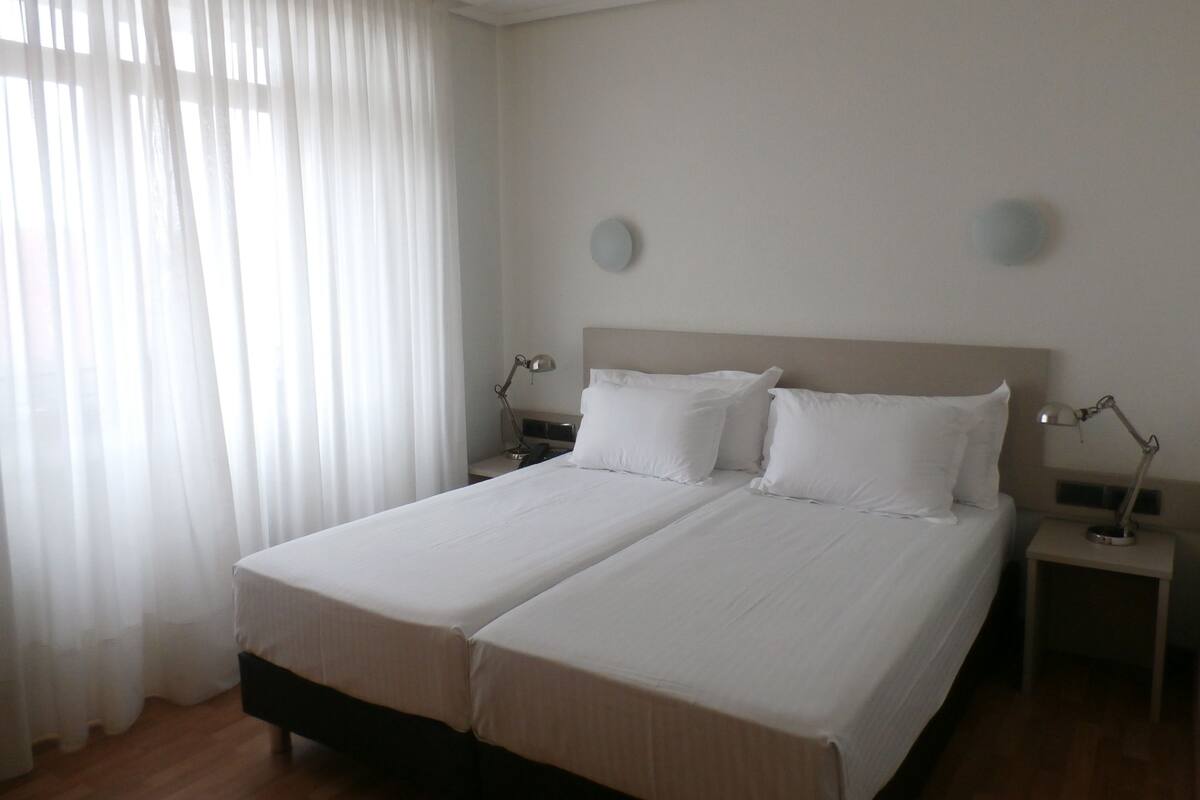 A double bed with white linens in a hotel room.