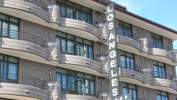Um hotel com vários andares e varandas, com uma placa indicando ser o Hotel Los Angeles.