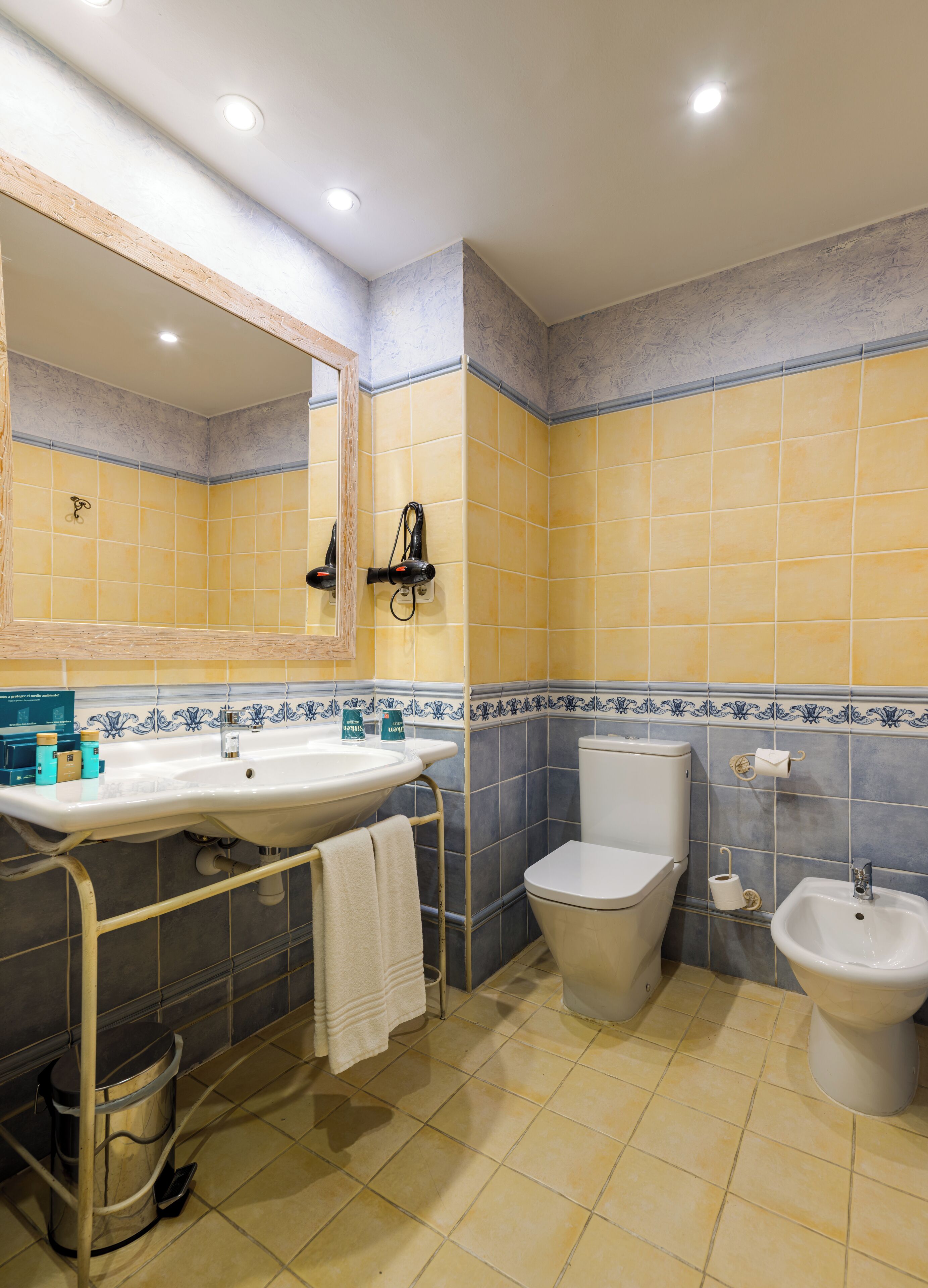A bathroom with a sink, toilet, bidet, and a mirror.