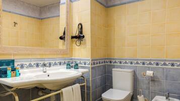 A bathroom with a sink, toilet, bidet, and a mirror.