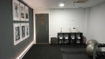 A gym with exercise equipment, a wall with framed pictures, and a door labeled "Gym + Relax".