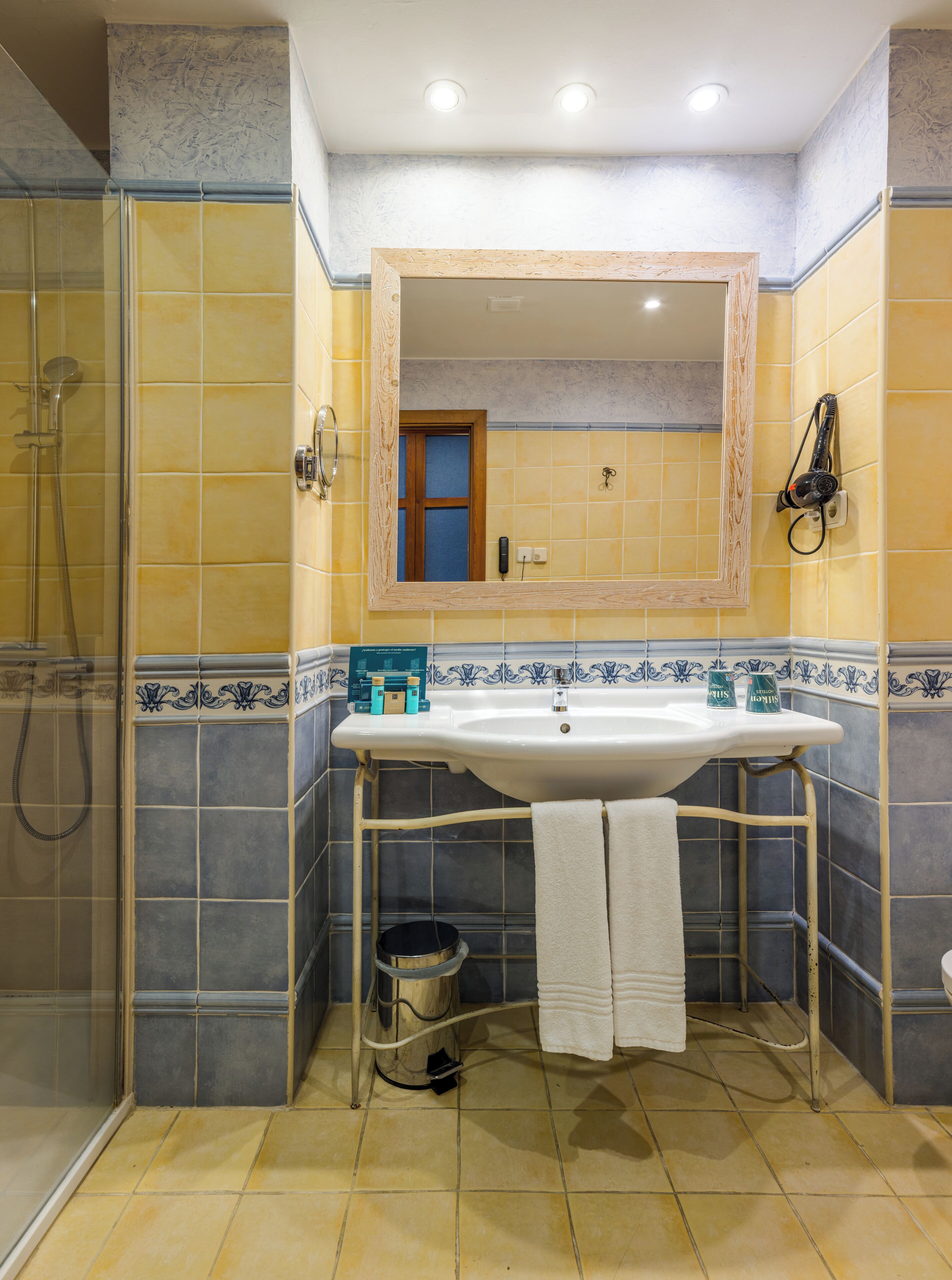 A bathroom with a sink, mirror, shower, and tiled walls.