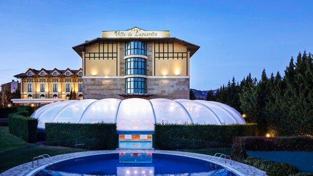 Un hotel con una amplia piscina, una estructura en forma de cúpula y un jardín bien cuidado.