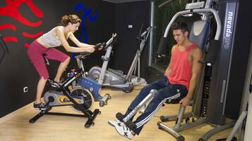 Une salle de sport équipée de vélos d’appartement, d’un tapis de course et d’appareils de musculation.