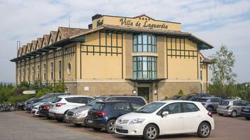 Hotellet Villa de Lagua med en parkeringsplads fyldt med biler.