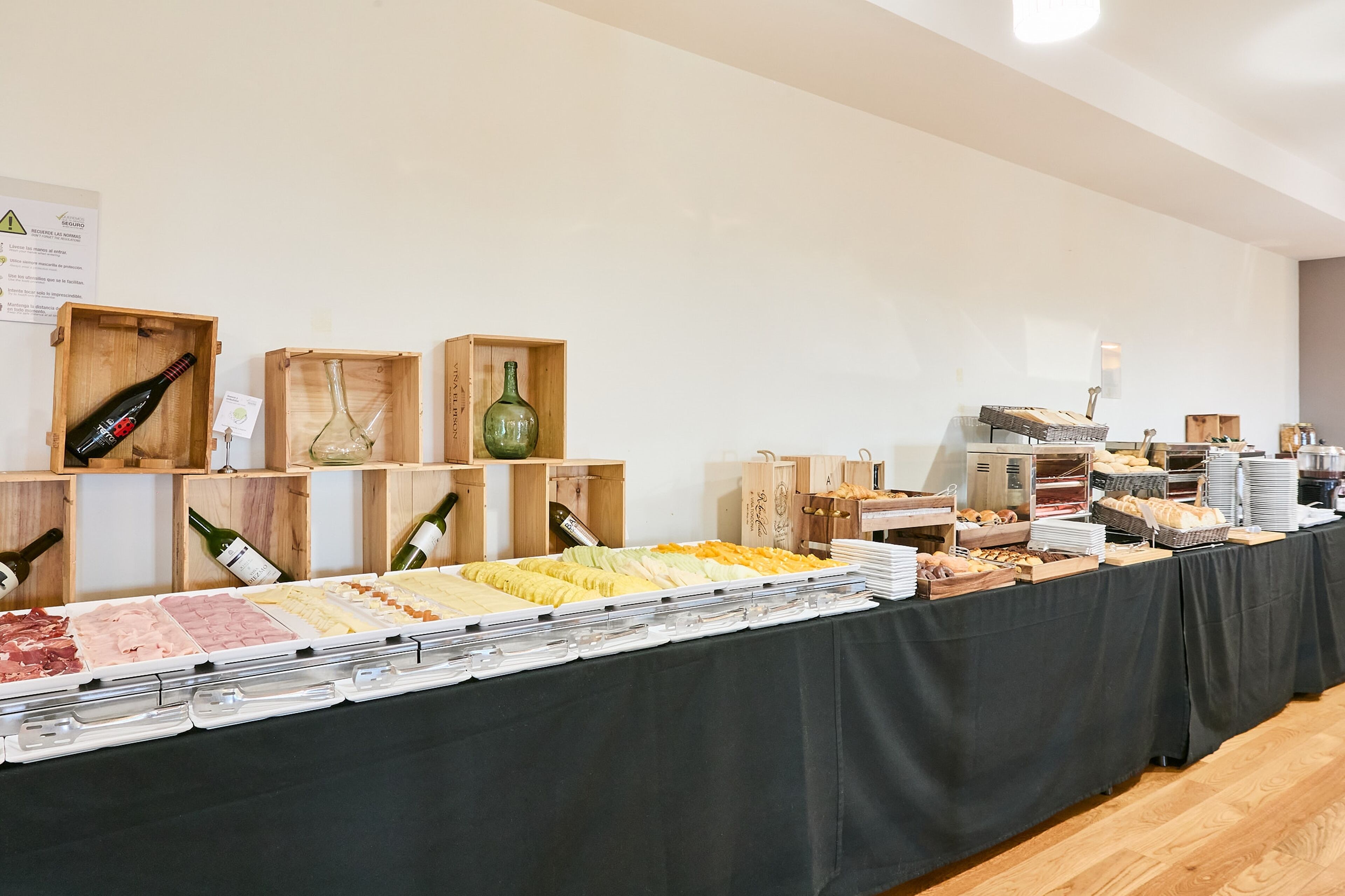 Montaje tipo bufé con diversos alimentos y botellas de vino en cajas de madera.