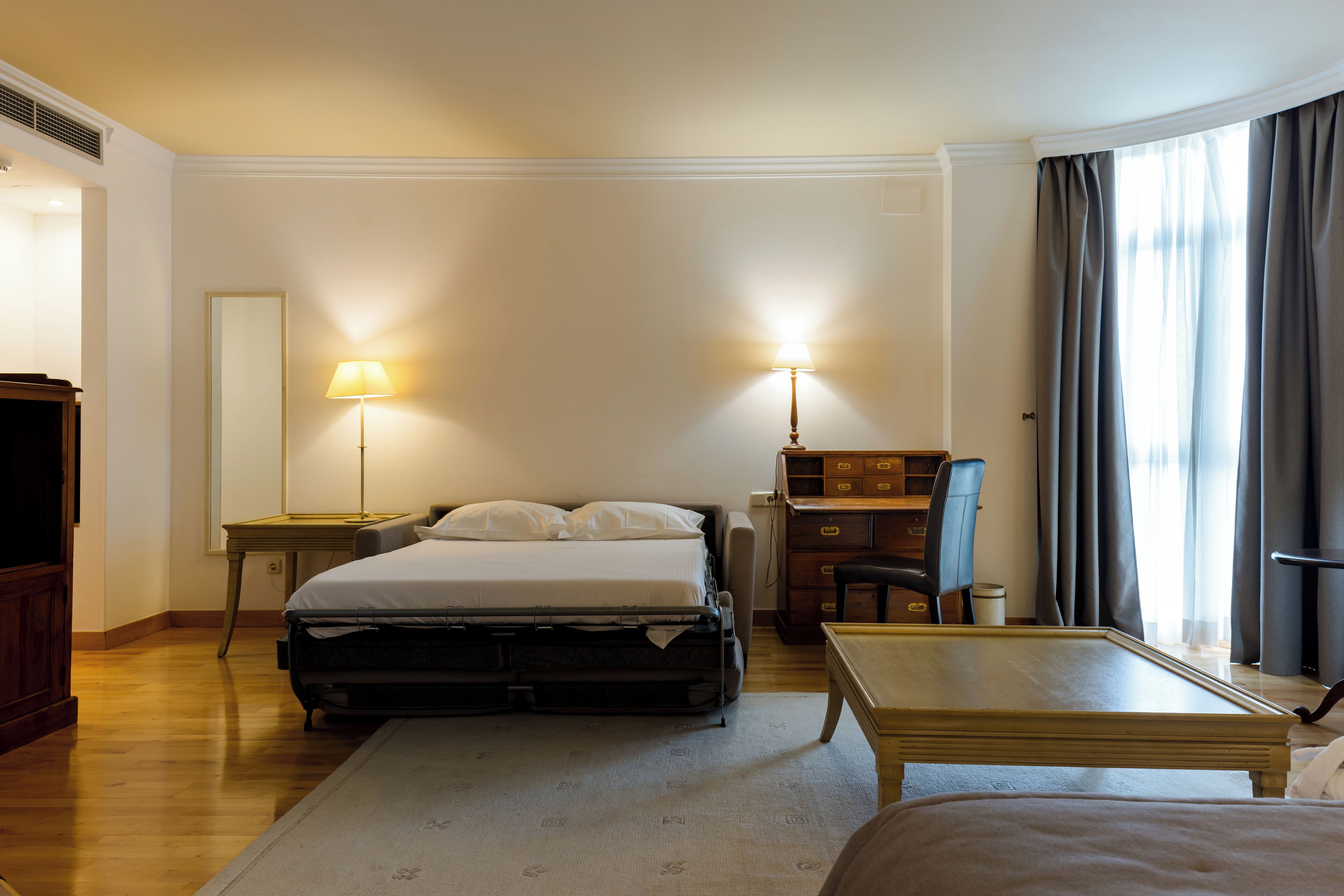 Une chambre d’hôtel avec un lit, des tables de chevet, un bureau et une chaise.