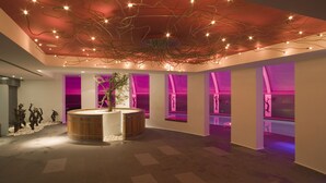 Un interior moderno con una estructura central de madera, iluminación ambiental y paredes de tono púrpura.