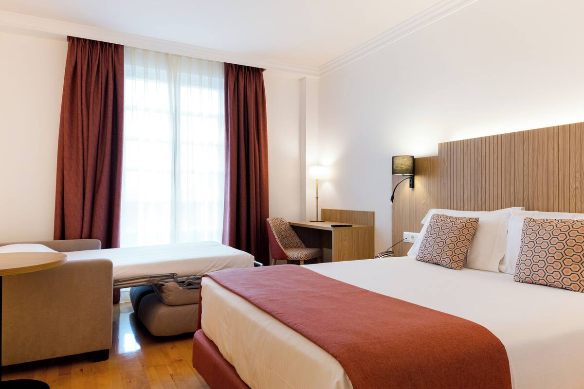 Une chambre d’hôtel avec un lit, un bureau, une chaise et une petite table.