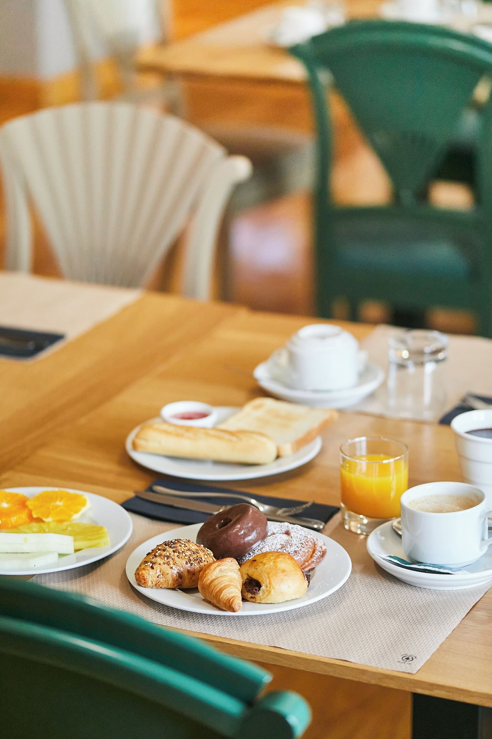 A breakfast table with croissants, fruit, and coffee.