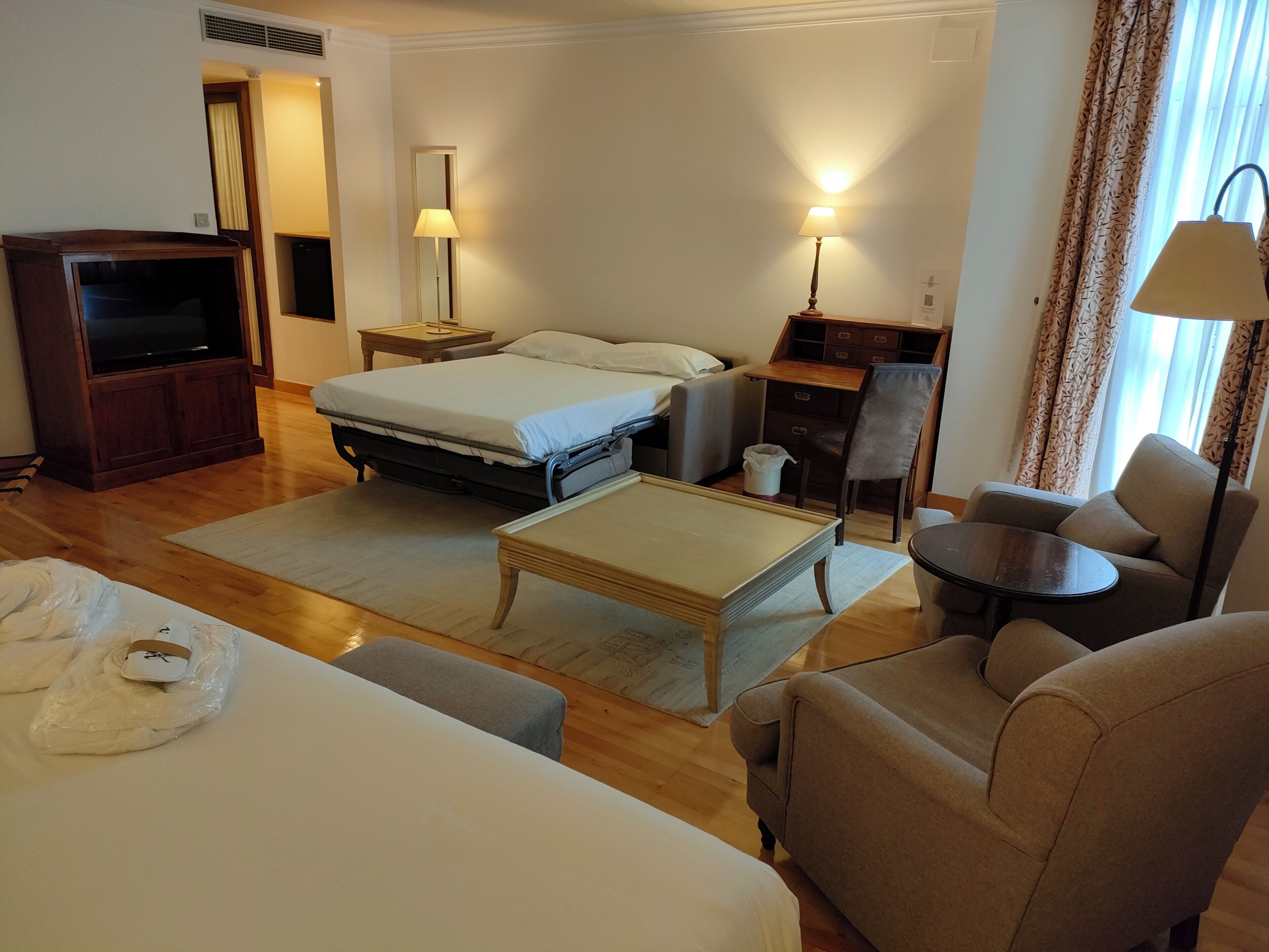 Una habitación de hotel con una cama, un escritorio, una silla, un televisor y una lámpara.