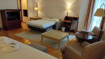 Una habitación de hotel con una cama, un escritorio, una silla, un televisor y una lámpara.