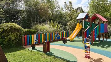 Un parque infantil con un sube y baja, un tobogán y una estructura para escalar.