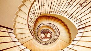 Una escalera en espiral con un espacio abierto en el centro, rodeada por una barandilla.
