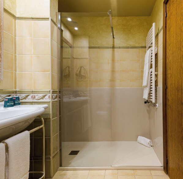 Un baño con ducha, lavamanos y un perchero para toallas.