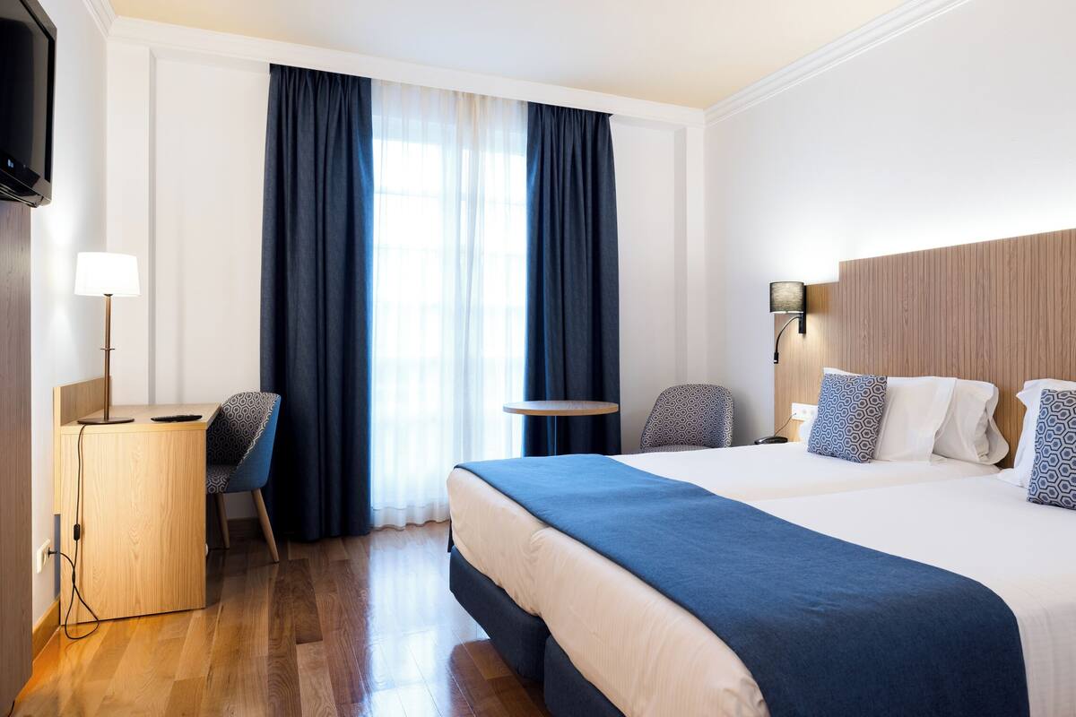 Une chambre d’hôtel avec un grand lit, un bureau avec une chaise, une télévision et une table de chevet.