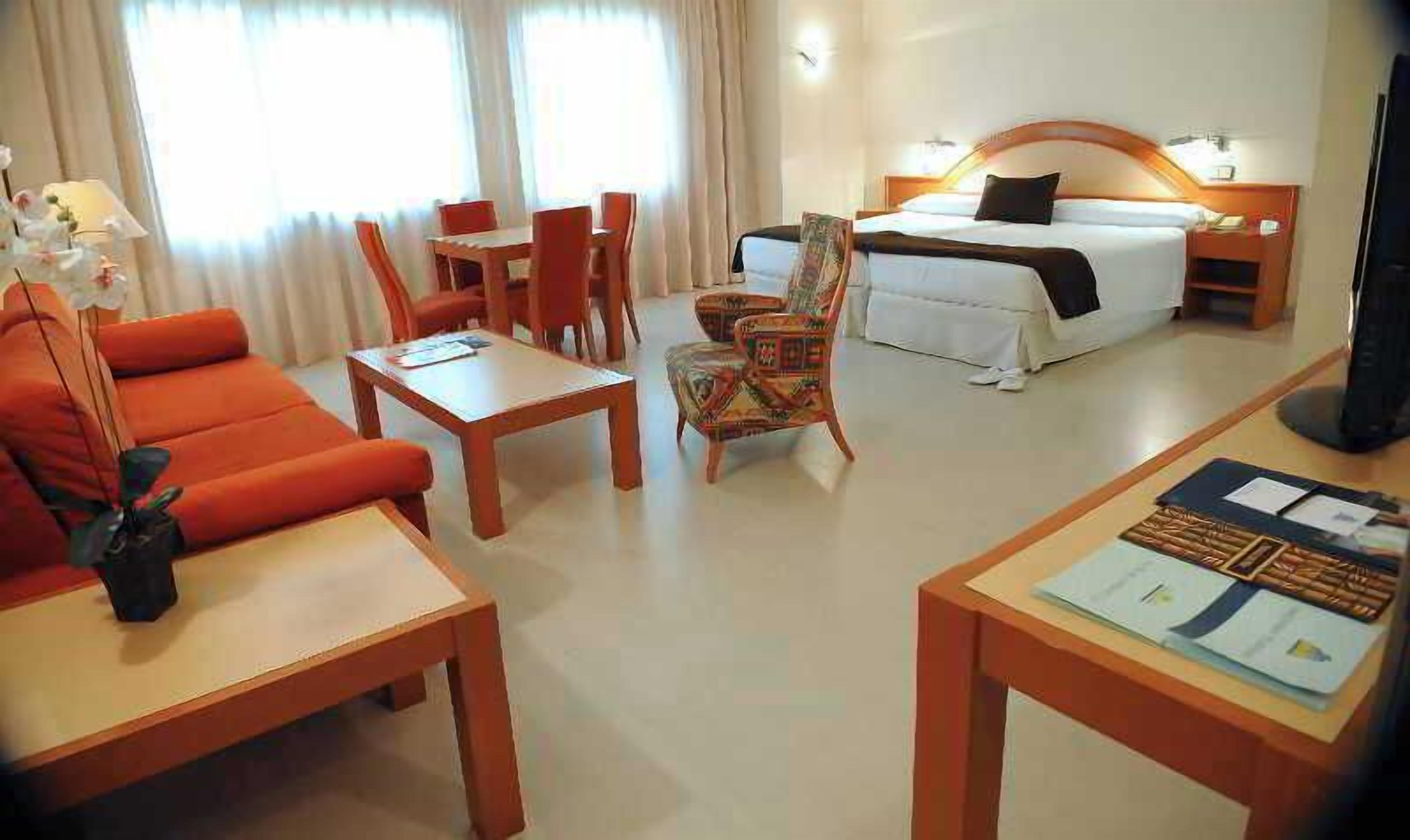 Una habitación de hotel con cama, escritorio, silla, sofá y televisor.