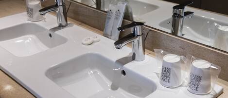 Un baño con dos lavamanos, un espejo y un dispensador de toallas.