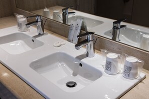 A bathroom with two sinks, a mirror, and a towel dispenser. - Hotel Palacio del Mar (Santander)