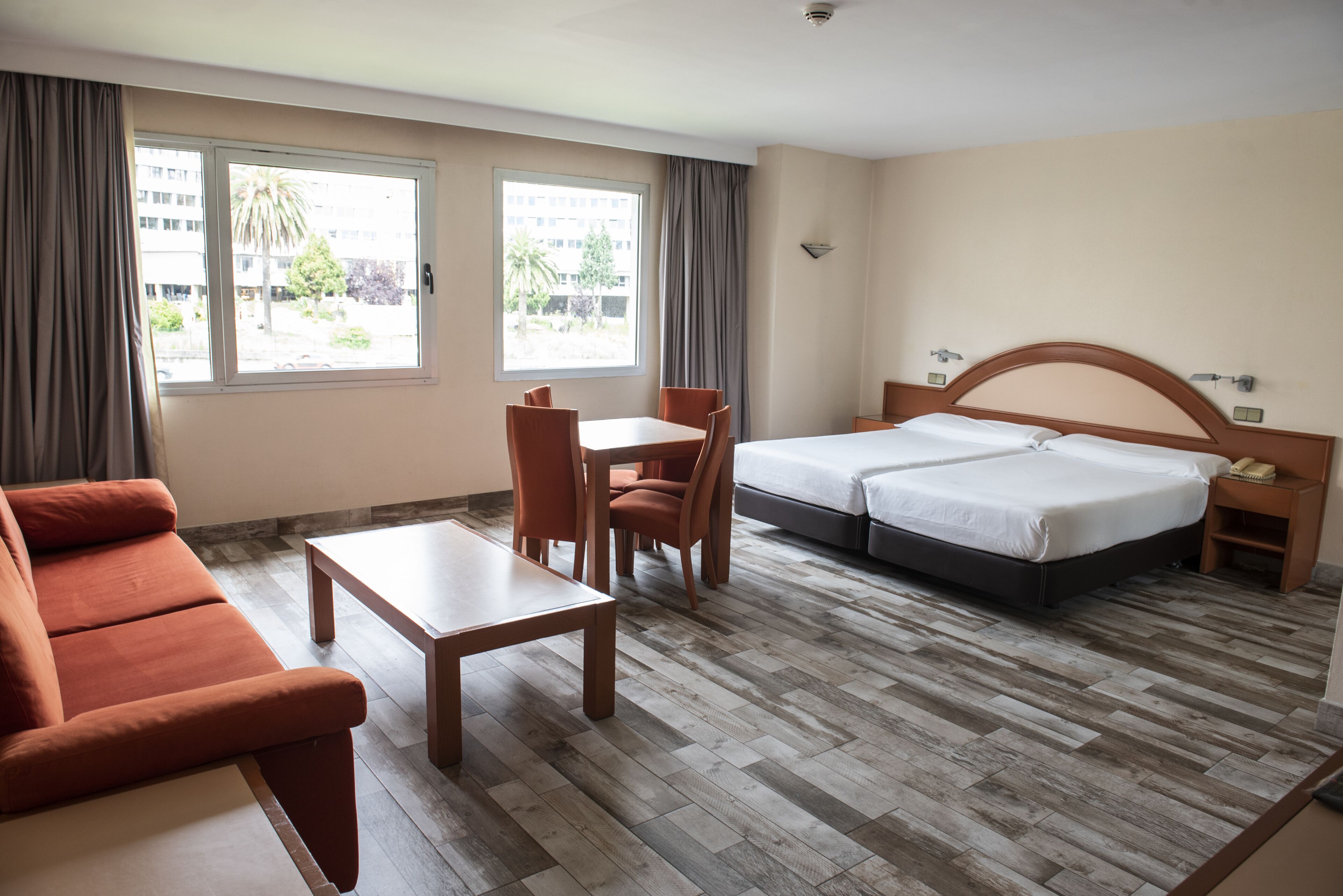 Habitació d'hotel amb un llit, un sofà, una taula i dues cadires.