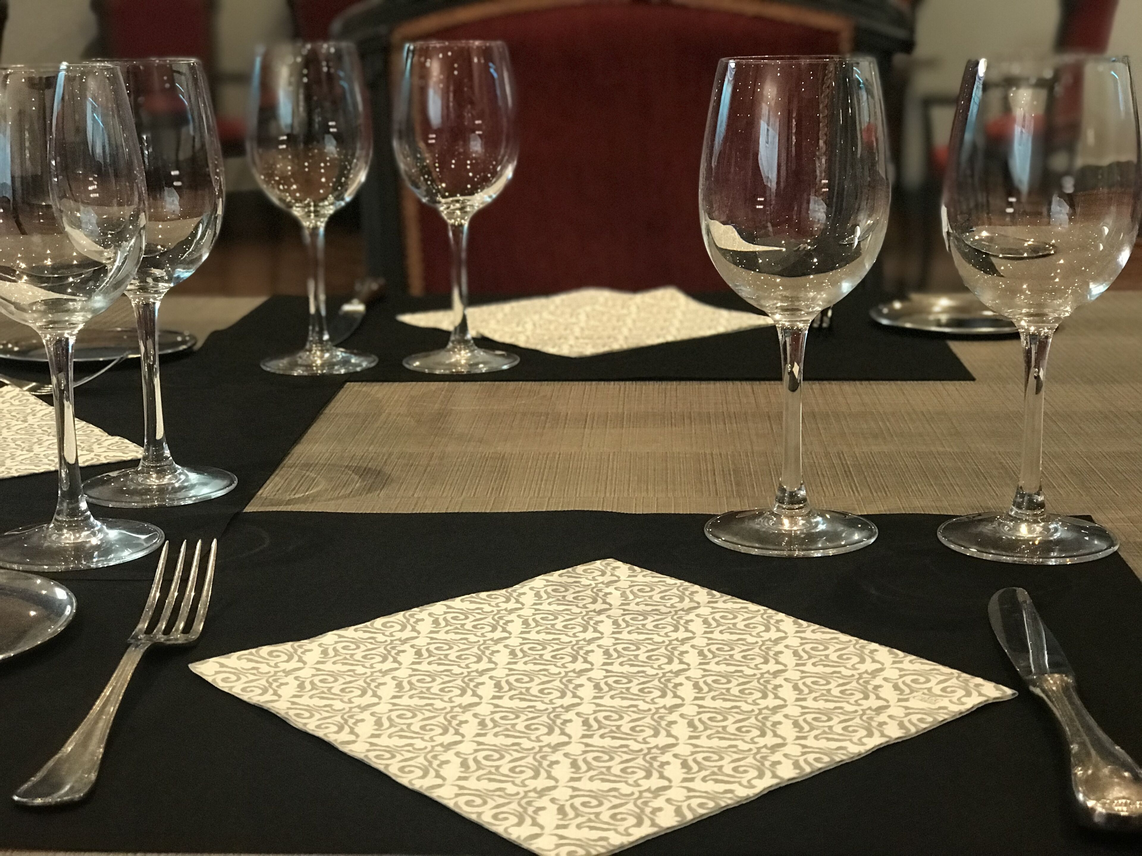 A table set with wine glasses, cutlery, and patterned napkins.