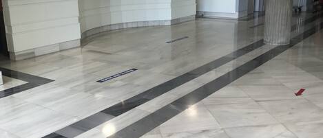 A clean, modern lobby with a reception desk, clear directional arrows on the floor, and a large pillar.