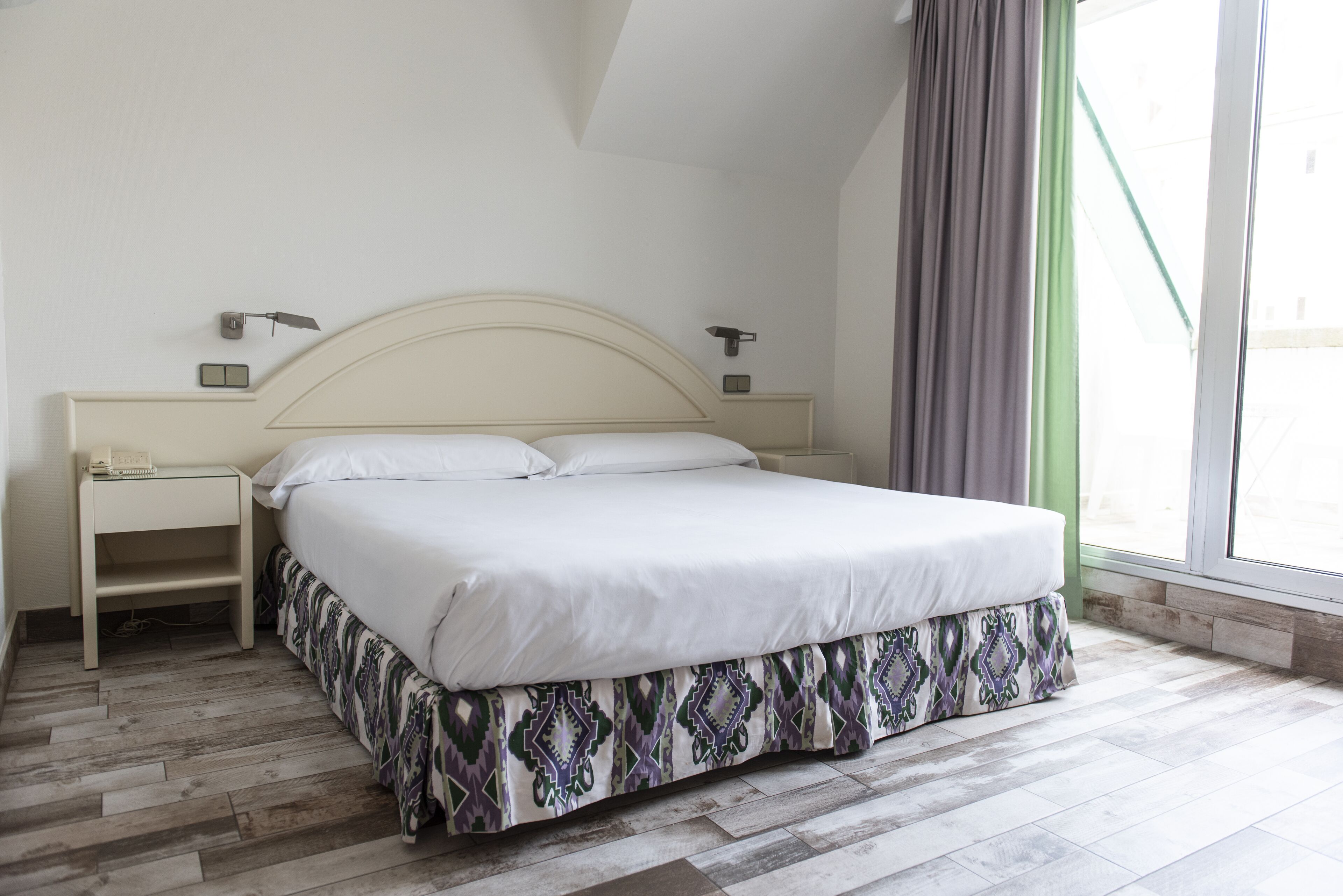A bedroom with a bed, nightstands, and a window with curtains.