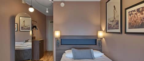 A modern bedroom with a bed, bedside lamps, a mirror, and wall art.