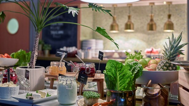 A buffet with various food items and a large potted plant.
