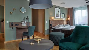 A hotel room with a bed, a desk with a telephone, a chair, a round table, and a large window with curtains.