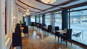 Un restaurante con una barra larga, sillas negras y candelabros.