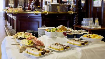 Una mesa de buffet con diferentes alimentos y una zona de bar al fondo.